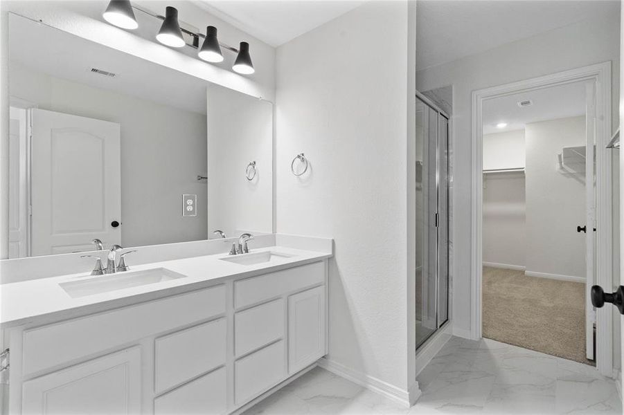 This primary bathroom is definitely move-in ready! Featuring a walk-in shower with tile surround, white stained cabinets with light countertops, spacious walk-in closet with shelving, high ceilings, custom paint, sleek and dark modern finishes.