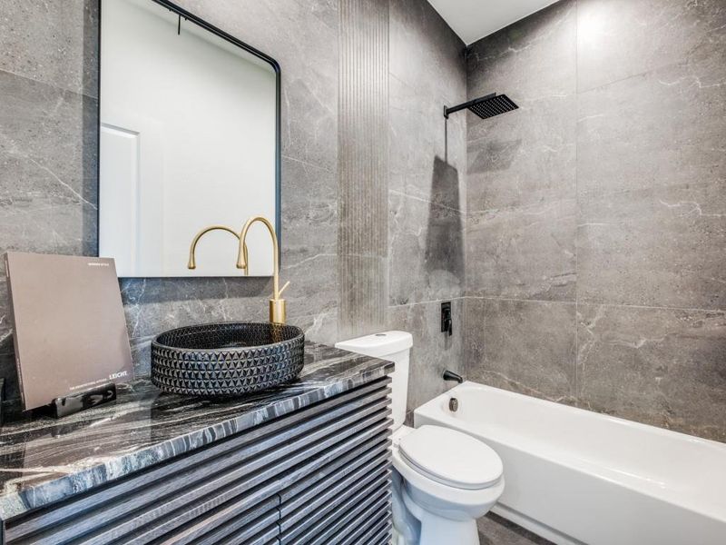 Full bathroom with tile walls, vanity, tiled shower / bath, and toilet