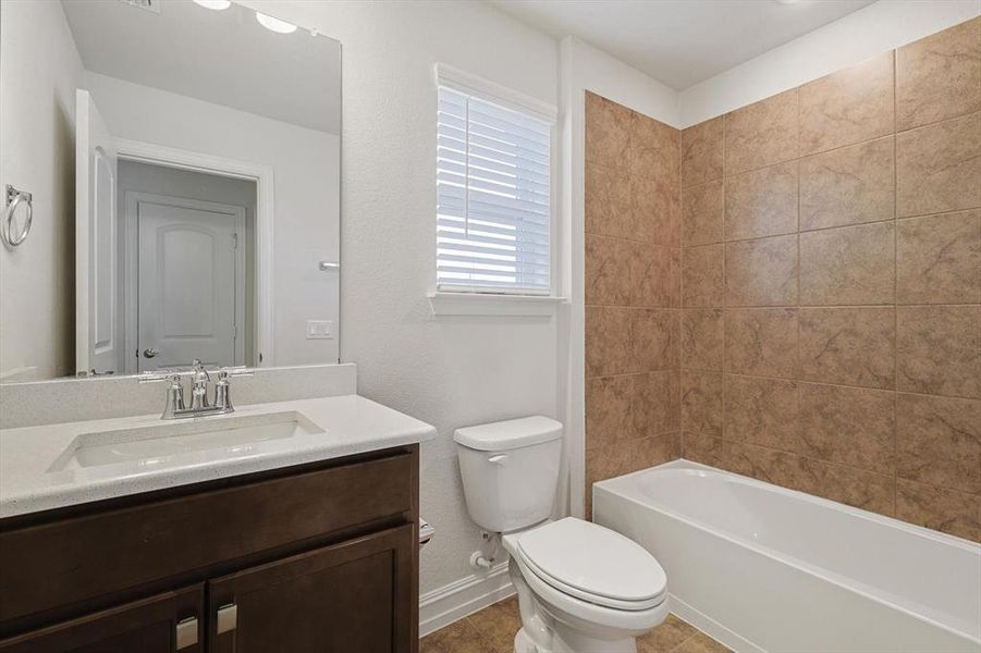 Full bathroom with tile patterned floors, vanity, toilet, and tiled shower / bath