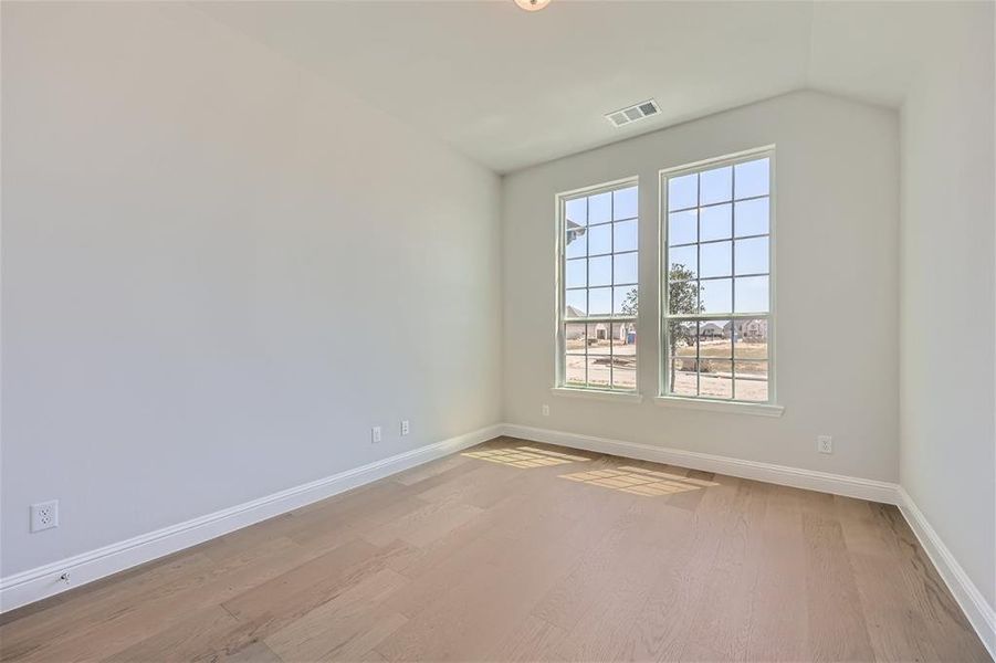 Empty room with a wealth of natural light and hardwood / wood-style floors