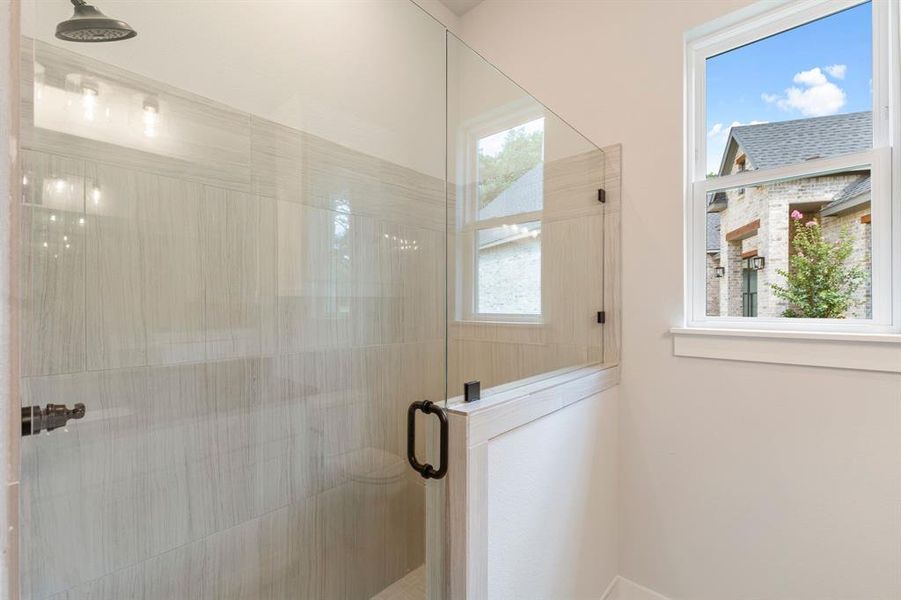 Bathroom featuring a shower with door and a wealth of natural light