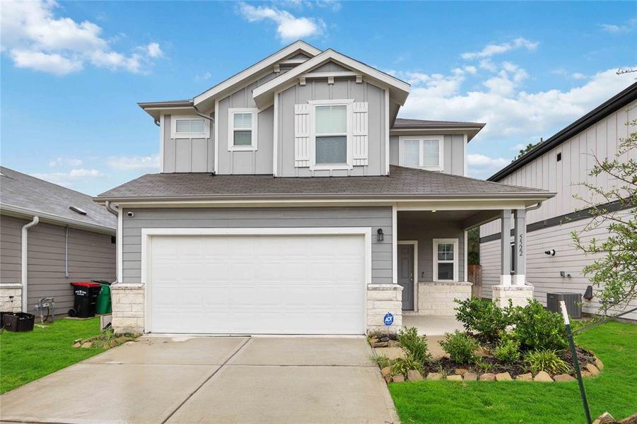 Modern two-story home with inviting curb appeal, featuring a manicured lawn, stone trim and a welcoming front porch with no back neighbors in a cul-de-sac.
