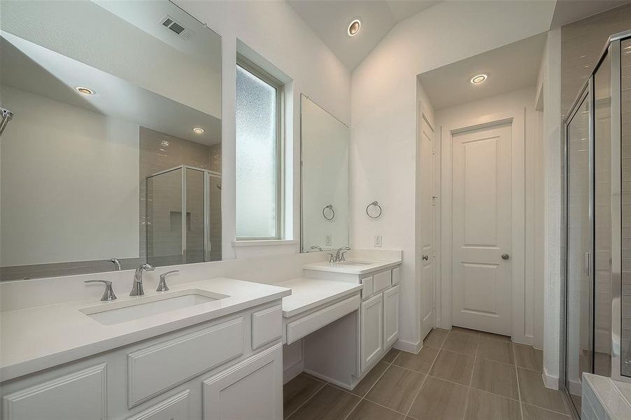 Primary bathroom features double-sinks, vanity area, separate shower & tub. Window provides substantial natural light. Door in front to walk-in closet.