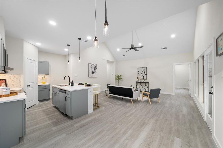 Kitchen with gray cabinetry, a center island with sink, decorative light fixtures, light wood-type flooring, and ceiling fan