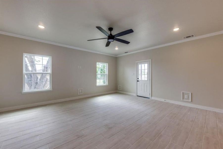 Empty room featuring light hardwood / wood-style floors, ornamental molding, and ceiling fan