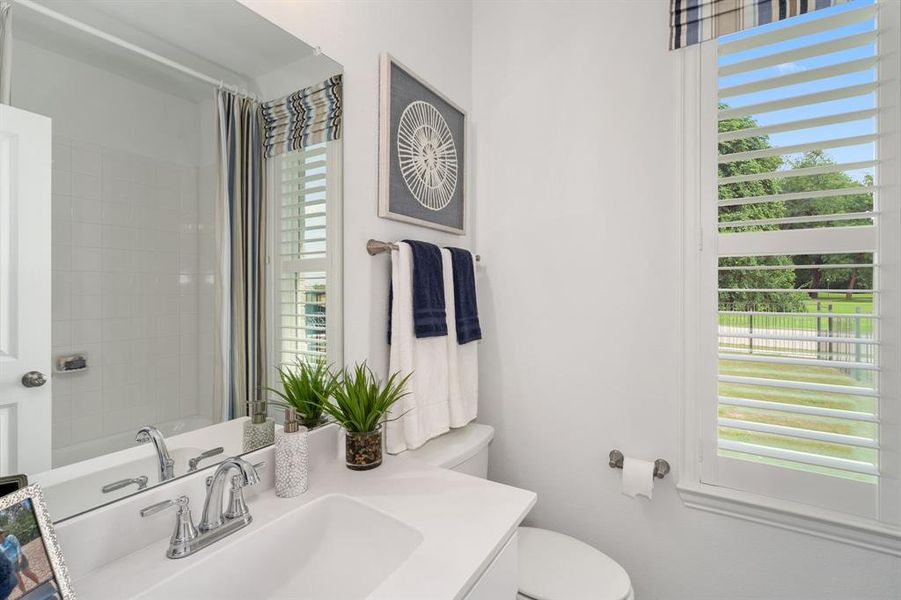 Bathroom featuring toilet, walk in shower, vanity, and a wealth of natural light