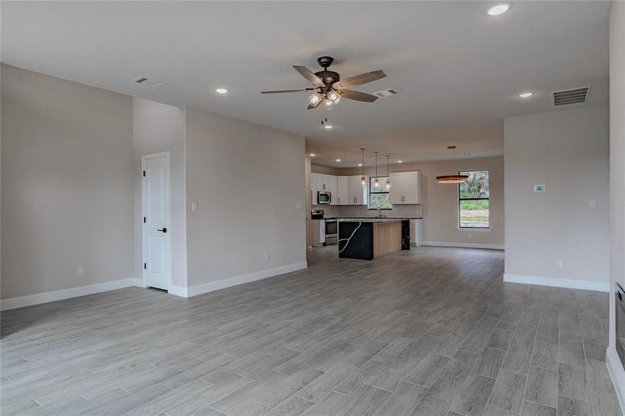 Unfurnished living room with light hardwood / wood-style floors and ceiling fan