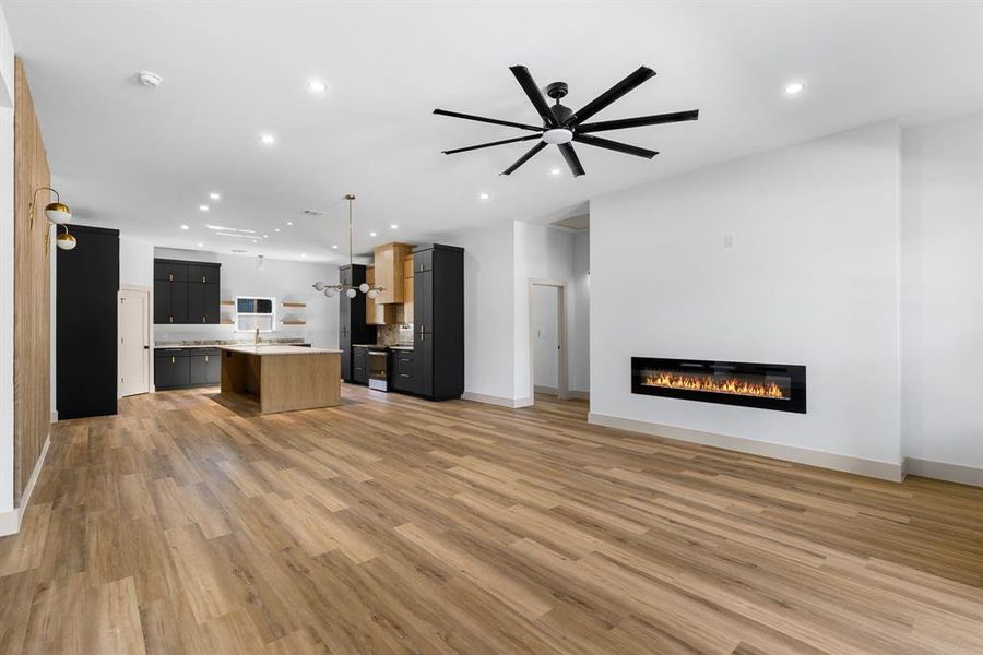 Unfurnished living room with ceiling fan and light wood-type flooring