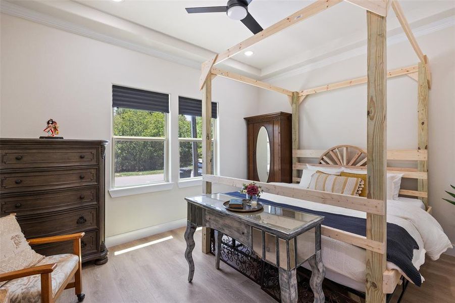 Bedroom featuring a raised ceiling, luxury vinyl floors, and ceiling fan