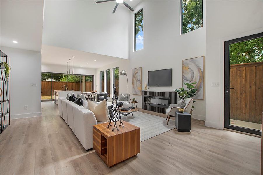 Living room with ceiling fan, light hardwood / wood-style floors, and a towering ceiling