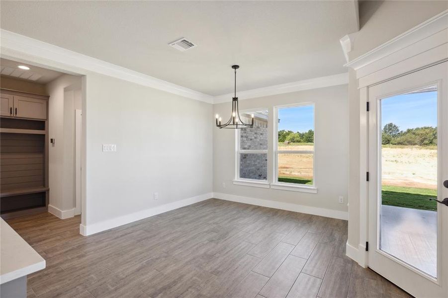 Unfurnished dining area featuring ornamental molding, a chandelier, and hardwood / wood-style floors