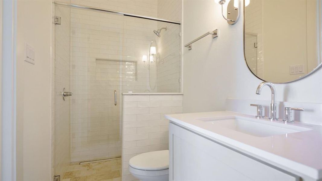 Bathroom featuring vanity, toilet, and a shower with shower door