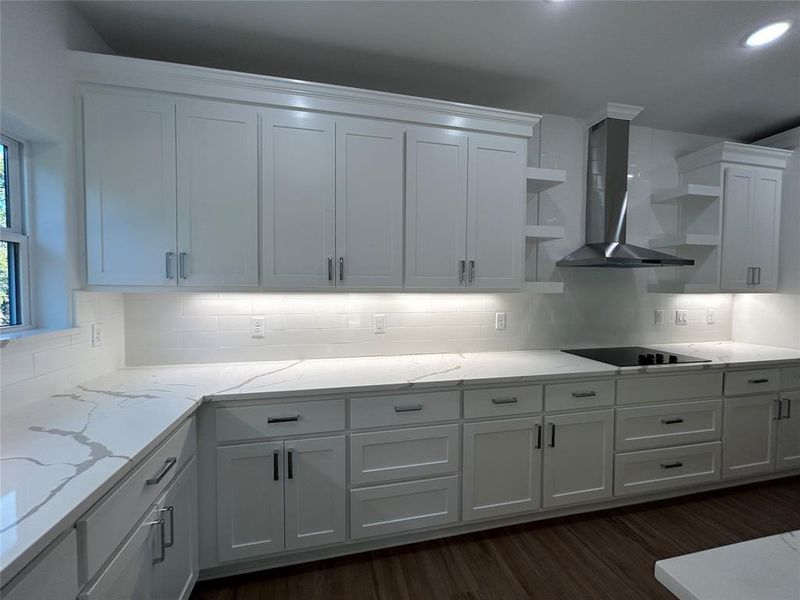 Kitchen with extractor fan, white cabinetry, dark wood-type flooring, and stovetop