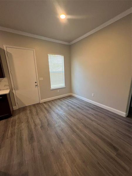 Empty room featuring ornamental molding and dark hardwood / wood-style floors