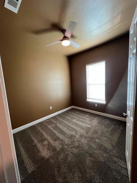 Unfurnished room with ceiling fan, carpet, and a textured ceiling