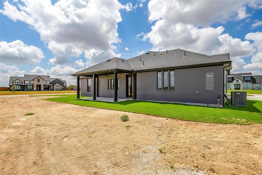 Rear view of property with cooling unit and a lawn