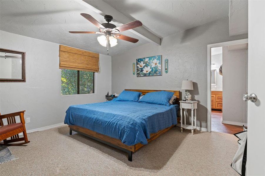 Spacious Primary bedroom with large ensuite bath, ceiling fan, and beam ceiling