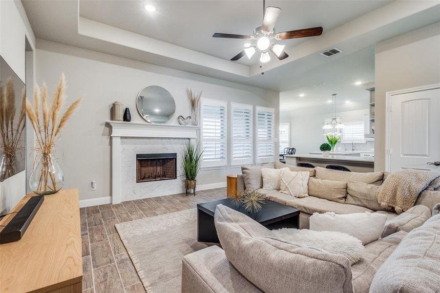 Living room featuring ceiling fan, a tray ceiling, and wood-type flooring