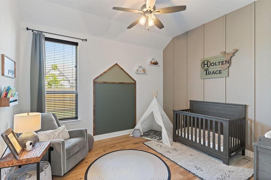 Bedroom with light hardwood / wood-style flooring, ceiling fan, vaulted ceiling, and a crib