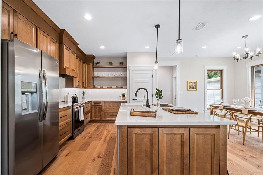 Custom maple wood cabinets in a pecan finish and soft close hardware coordinate beautifully with the wood floors throughout the home.