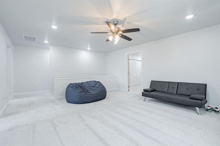 Living area with light colored carpet and ceiling fan