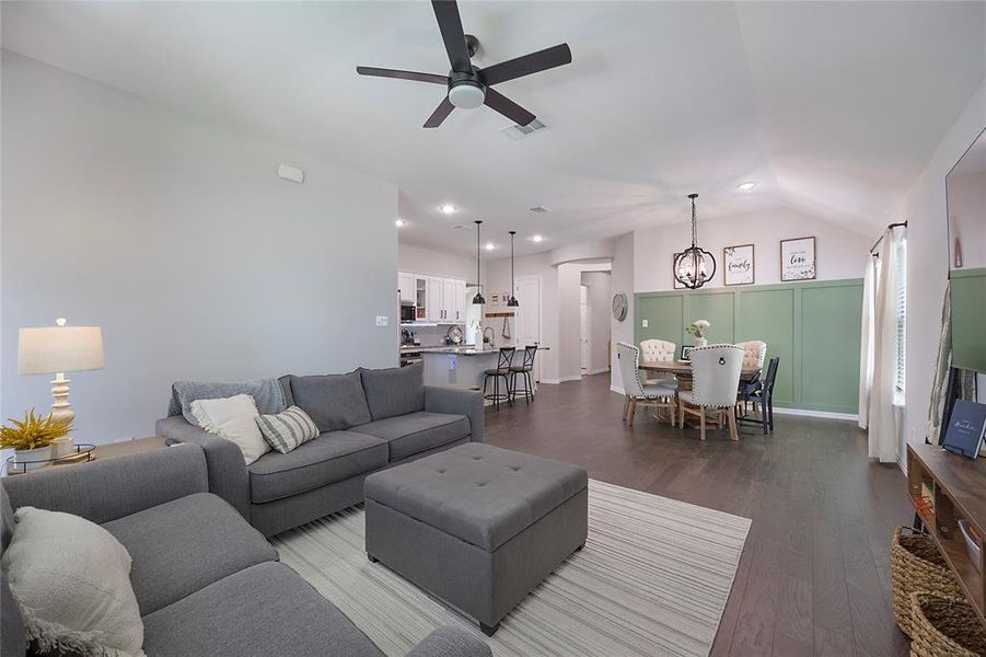 Living room featuring vaulted ceiling, ceiling fan with notable chandelier, and hardwood / wood-style floors