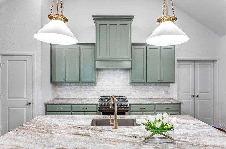 Kitchen with stainless steel stove, hanging light fixtures, and green cabinetry