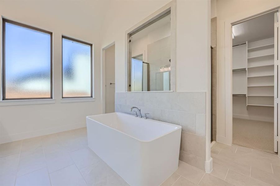 Bathroom featuring tile walls, tile patterned floors, and shower with separate bathtub