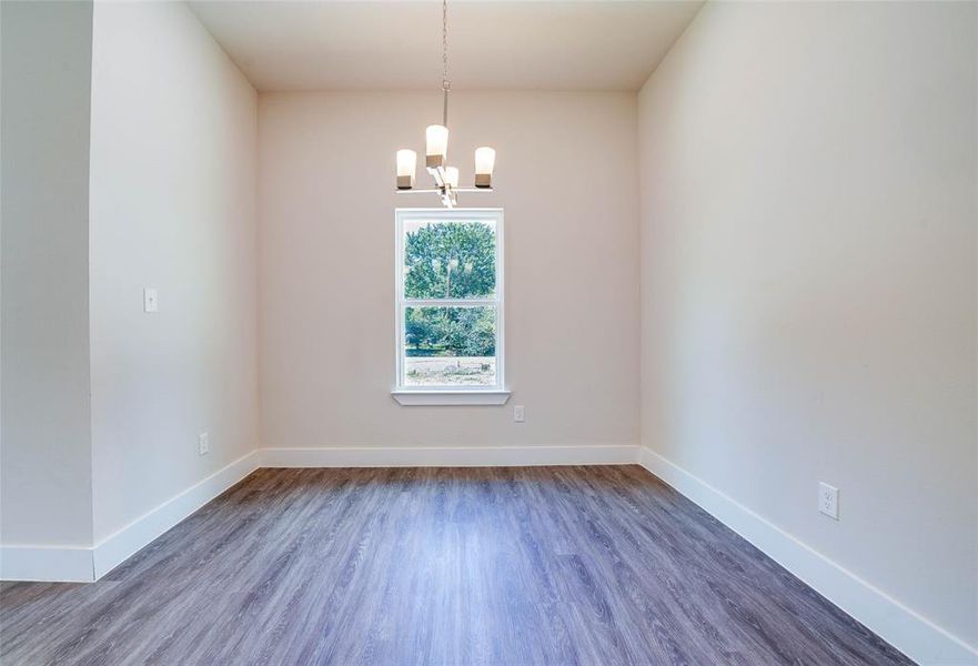 Empty room with an inviting chandelier and hardwood / wood-style floors