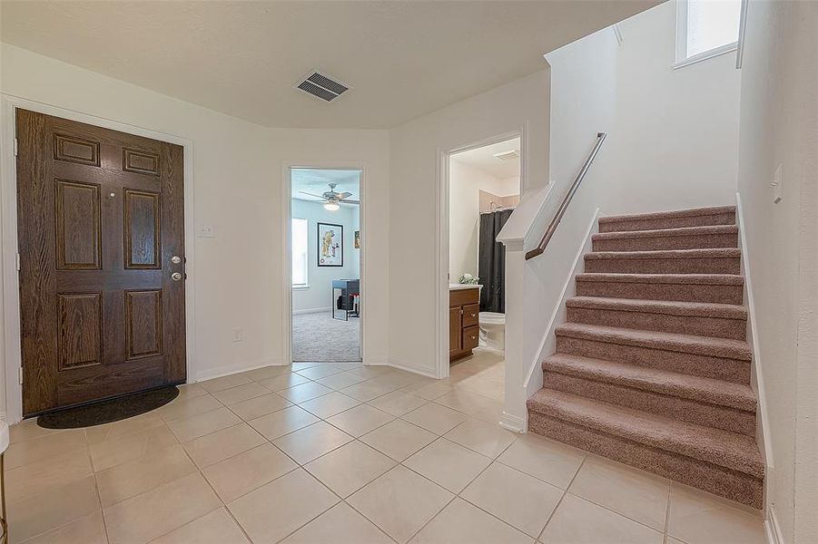 Office / bedroom, full bathroom, and stairway conveniently located in entryway