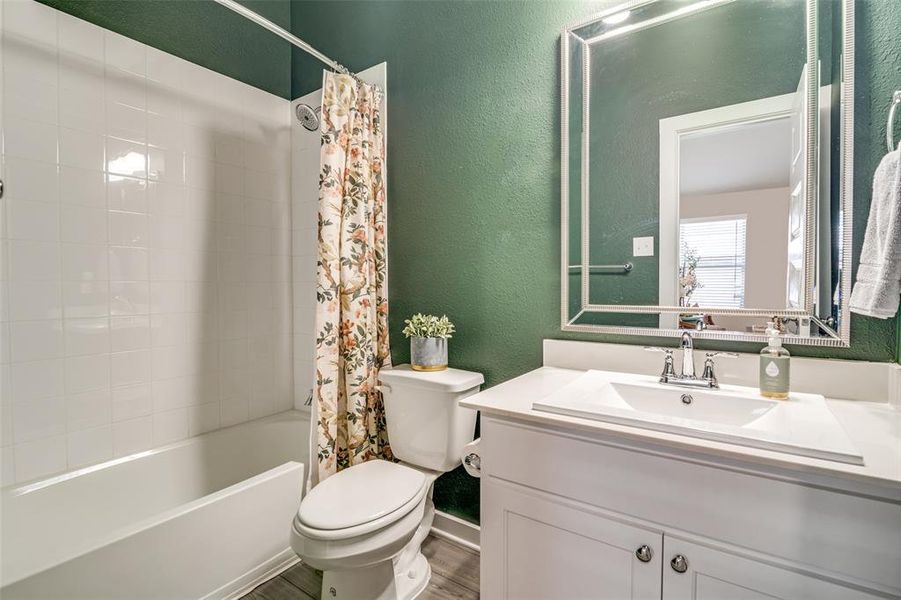 Full bathroom with shower / bathtub combination with curtain, wood-type flooring, vanity, and toilet