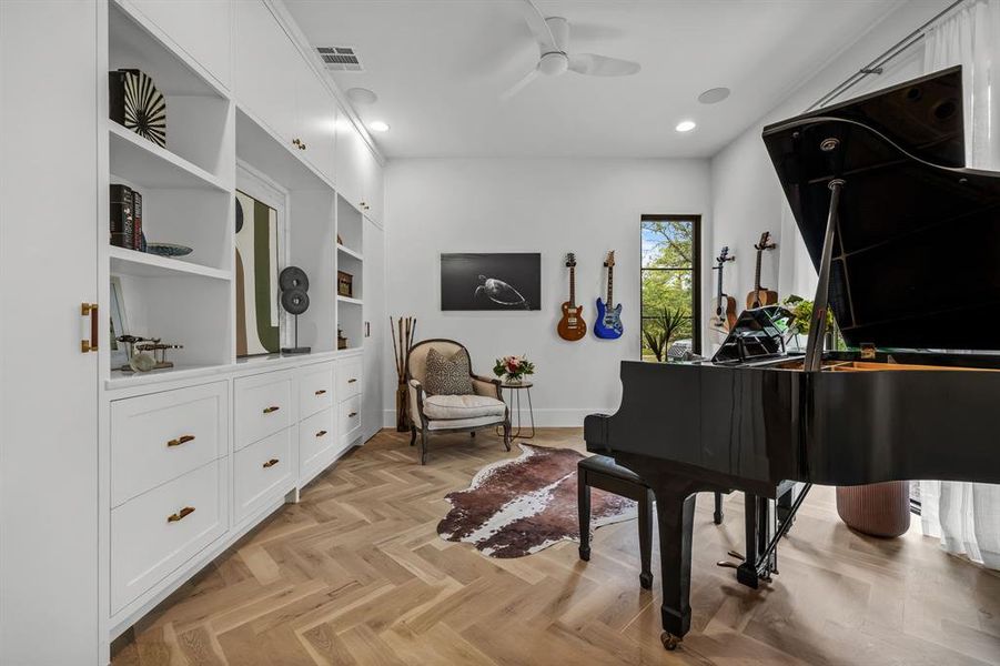 Miscellaneous room with built in shelves, ceiling fan, and light parquet floors