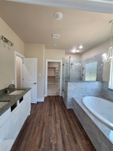 Bathroom with a textured ceiling, independent shower and bath, vanity, and hardwood / wood-style flooring