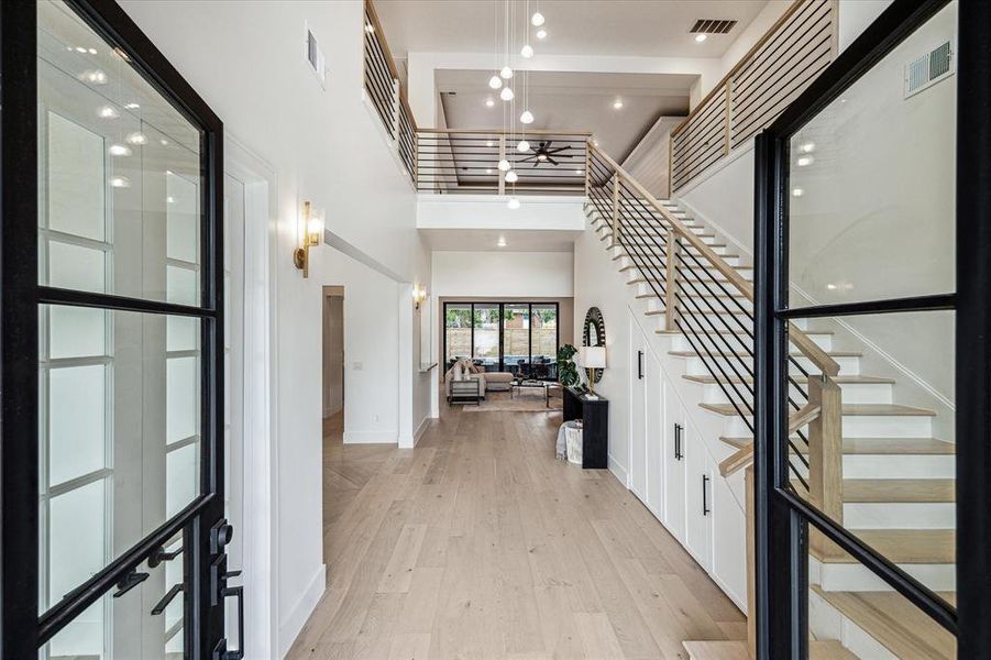 An inviting entryway features striking 8 ft black iron/glass double doors and reveals majestic views of the pool, summer kitchen, covered patio and artificial turf