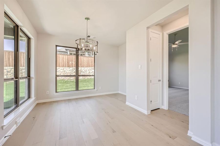 Unfurnished dining area with light hardwood / wood-style flooring and ceiling fan with notable chandelier