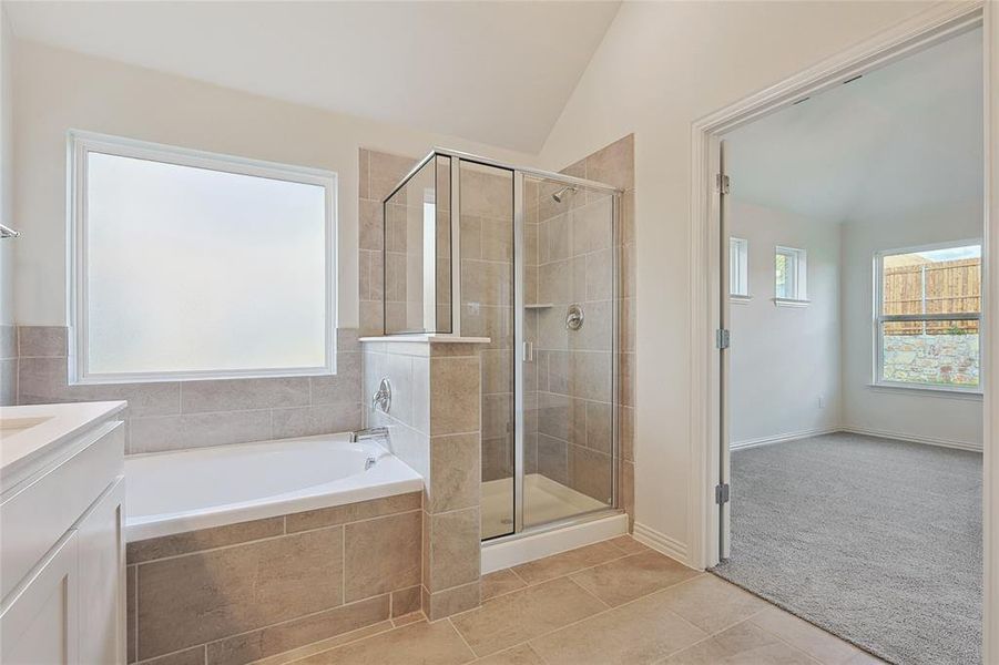 Bathroom featuring vanity, lofted ceiling, independent shower and bath, and tile patterned flooring