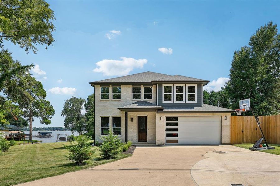 View of front of house featuring a water view, a garage, and a front yard