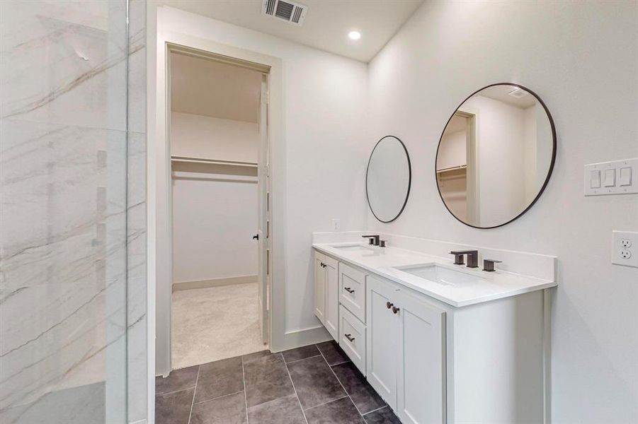 Bathroom featuring vanity, tiled shower, and tile patterned floors