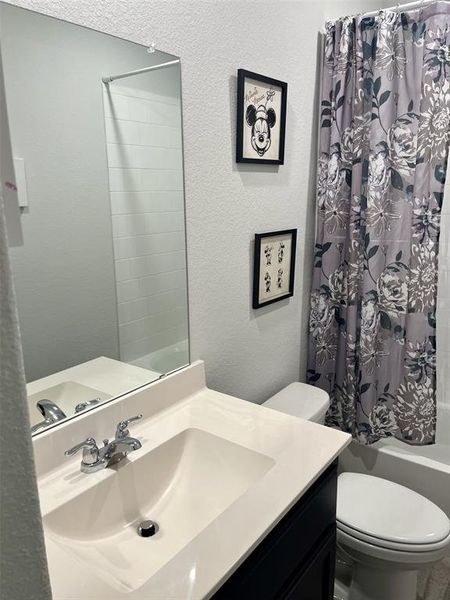 Full bathroom featuring vanity, shower / bath combination with curtain, and toilet