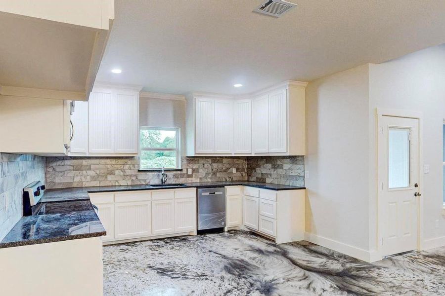 Kitchen with white cabinets, sink, stainless steel dishwasher, decorative backsplash, and electric range