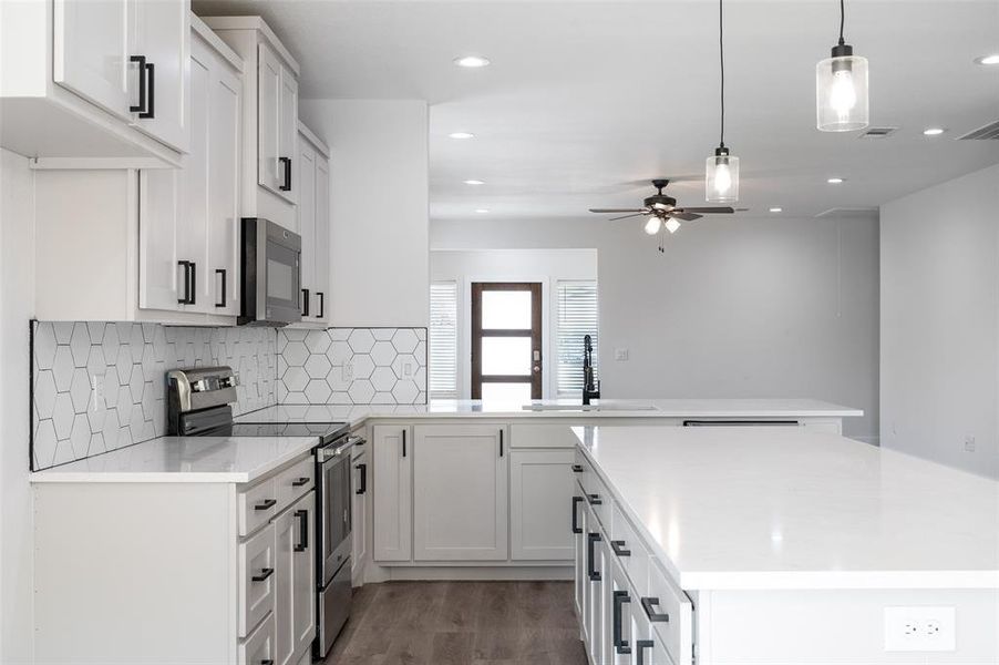 Kitchen with tasteful backsplash, stainless steel appliances, hardwood / wood-style floors, sink, and kitchen peninsula