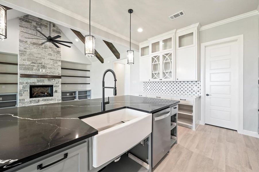 Kitchen featuring white cabinetry, a fireplace, ceiling fan, light wood-type flooring, and beam ceiling