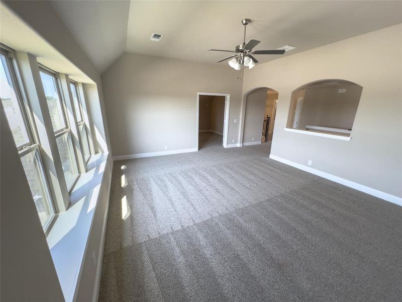 Spare room with ceiling fan, vaulted ceiling, and dark carpet