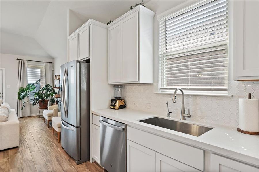 View of kitchen window, deep stainless sink, with quartz counter tops