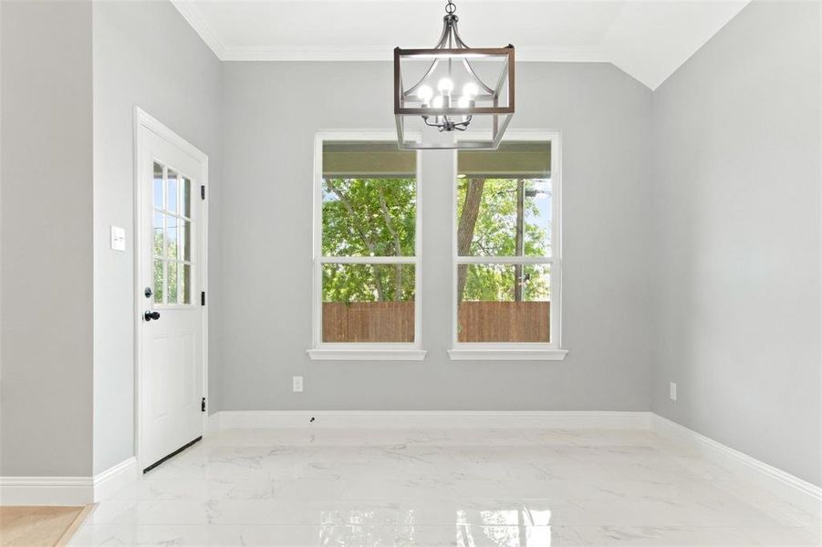 Unfurnished dining area featuring lofted ceiling, an inviting chandelier, and ornamental molding