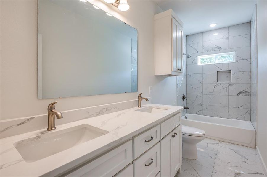 Full bathroom featuring tiled shower / bath, vanity, and toilet