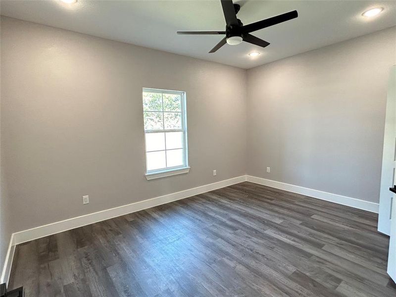 Empty room with ceiling fan and dark wood-type flooring