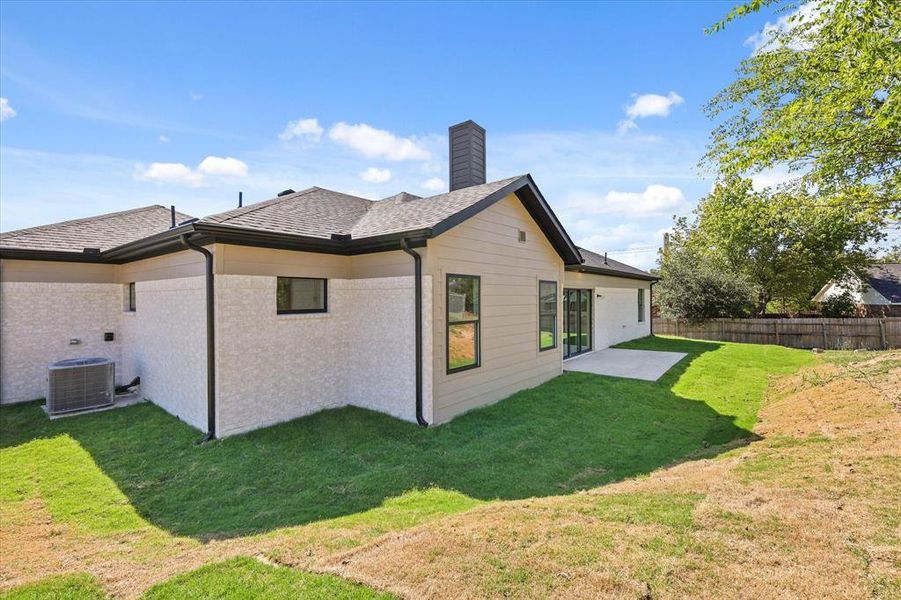 Back of house with a lawn, a patio.