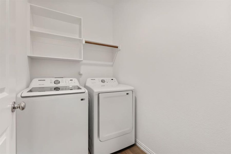 Clothes washing area with washer and clothes dryer and hardwood / wood-style flooring