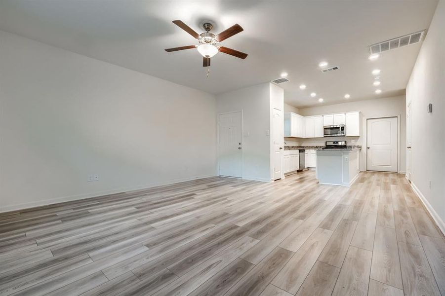 Unfurnished living room with light wood-type flooring and ceiling fan